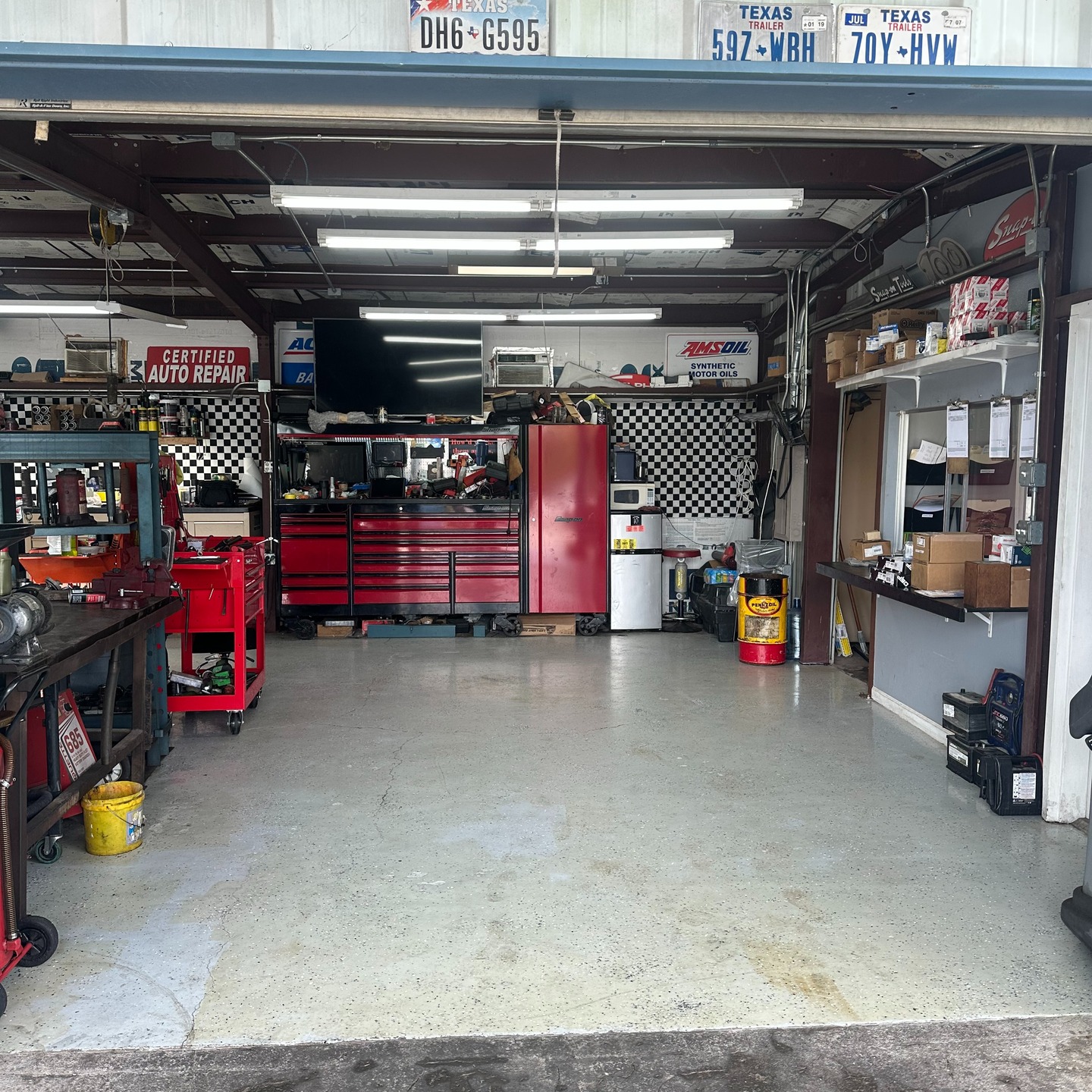 Inside Manchaca Garage’s freshly cleaned workshop, with red tool cabinets, a checkered wall, and an open repair bay